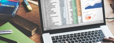 Un ordinateur ouvert avec une personne qui utilise Microsoft Excel, on voit des données, des graphiques etc